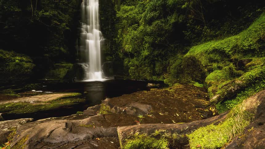 Freefall waterfall through the mountains with mosses around