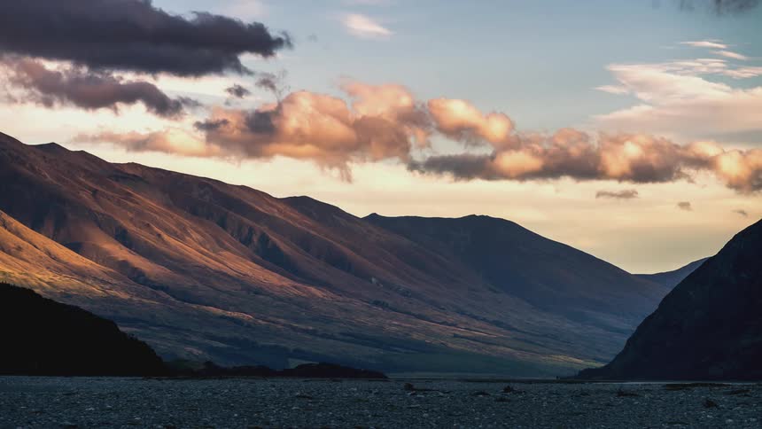 A timelapse of clouds over a mountain at sunset