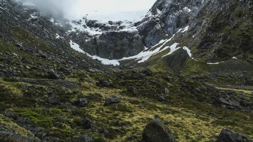 Low lying clouds flow over uneven mountain slopes during winter