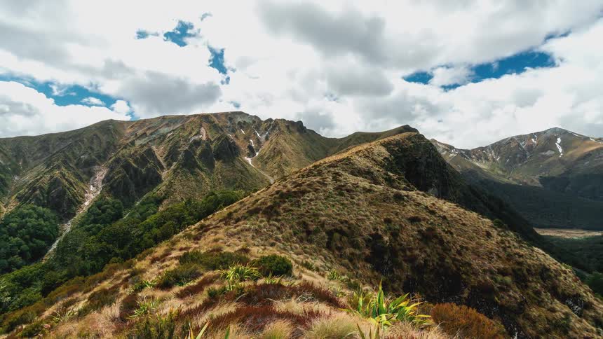 Mountain range with greenish cliffs and clouds passing by