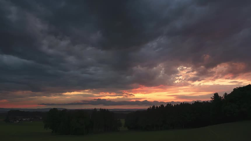 Time lapse of dark clouds rolling ove the landscape at sunset