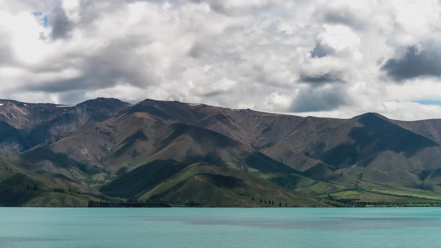 Clouds passing above mountains by a lake