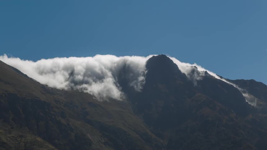 Imposing mountain peak with dense white clouds surrounding the summit