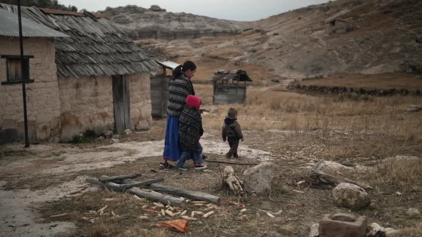 A mother walks two children outside their house