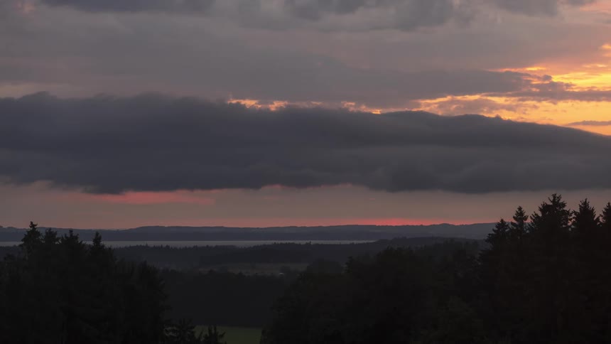 Silhouette of a forest against a red sky with the setting sun