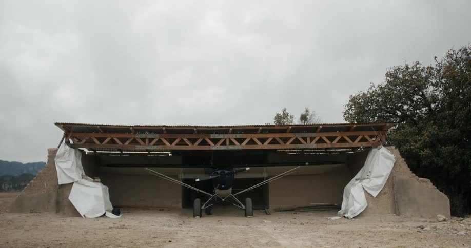 A small airplane is parked under a covering
