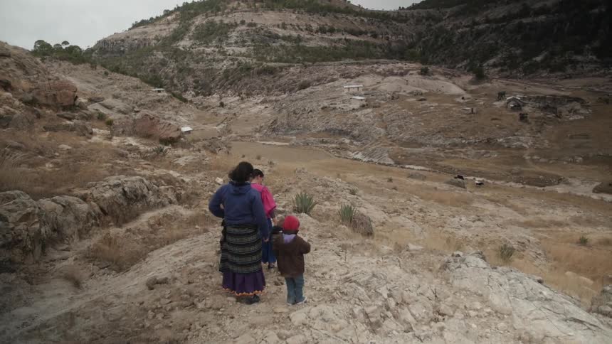 Two adults and a child walking through a rocky wilderness
