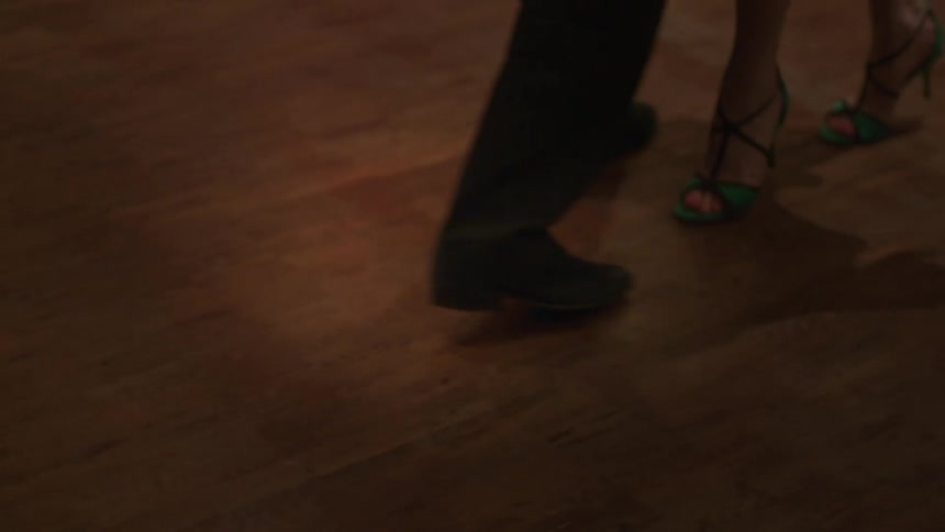 A couple dance together on a hardwood floor