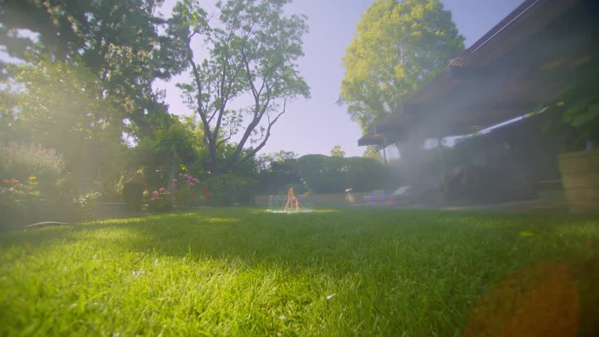 Little girl playing in the backyard of a house with grass and trees around