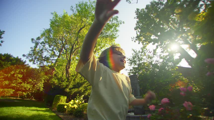 A young boy smiles while running through a yard