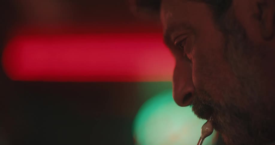 Concentrated bearded man blowing into a heated glass tube