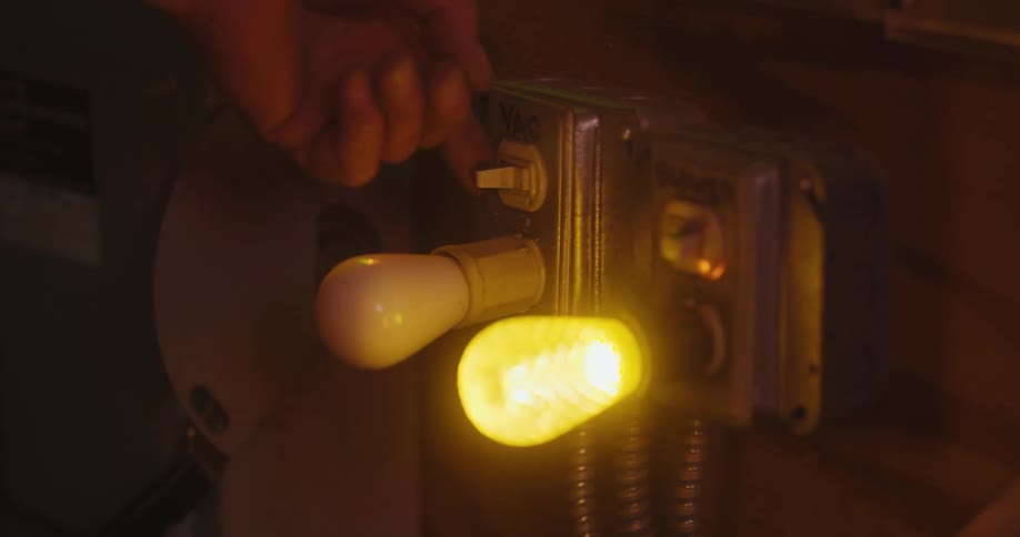 A human hand flipping a switch that turns on a light bulb