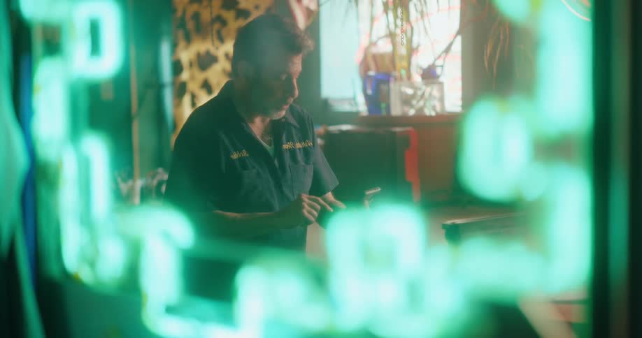 Man inside a room using his cell phone with neon lights on the wall
