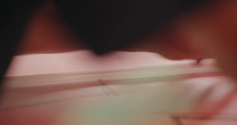 A man sketches on a piece of paper using a pencil and ruler