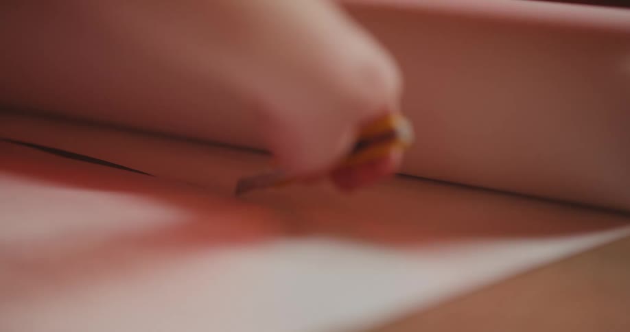 Closeup of a persons hand with a utility knife cutting a piece of paper