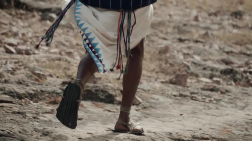 A person in sandals runs down a rocky path