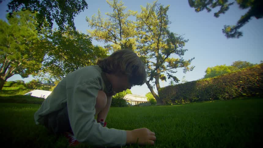 A child picks a piece of grass and hands it off