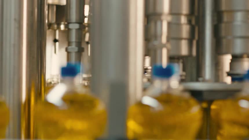 Close up of a vegetable oil production line with plastic bottles moving around