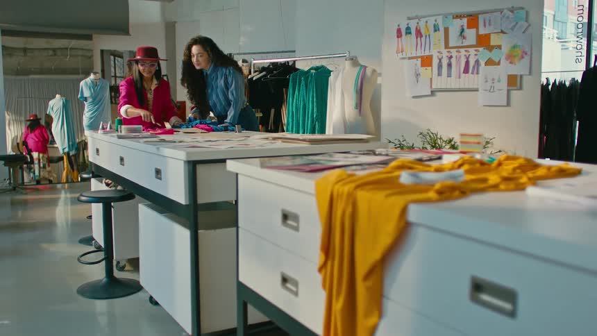 A brightly lit fashion design studio with garments and fabrics on tables