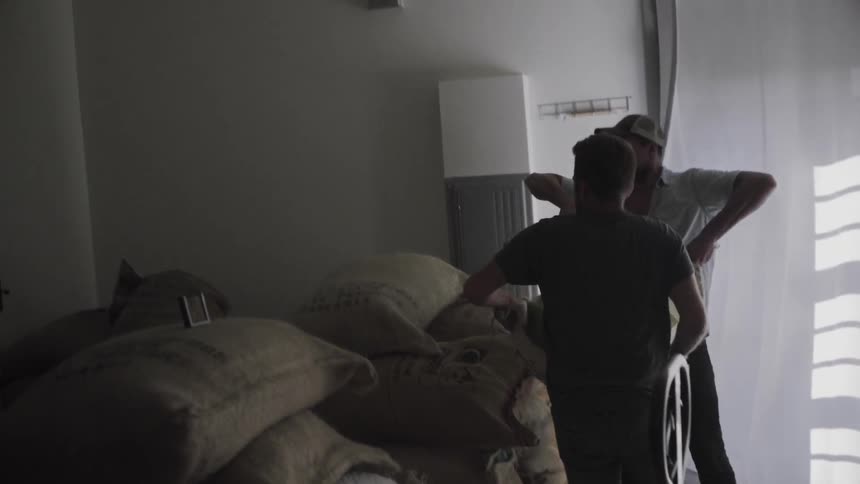 Two men stack big bags indoors