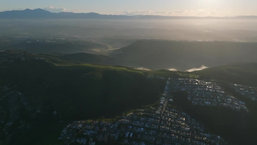 Aerial landscape of a city built on a hill with sunrise on the horizon