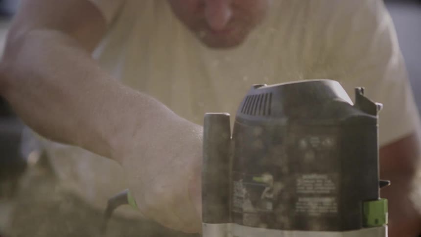 Man saws at something with sawdust flying up
