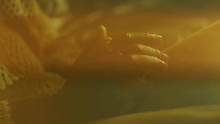 Closeup of a seated persons hand and the reflection of sunlight