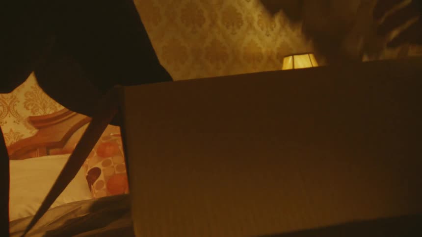 Two people removing objects from a box on the bed in the bedroom