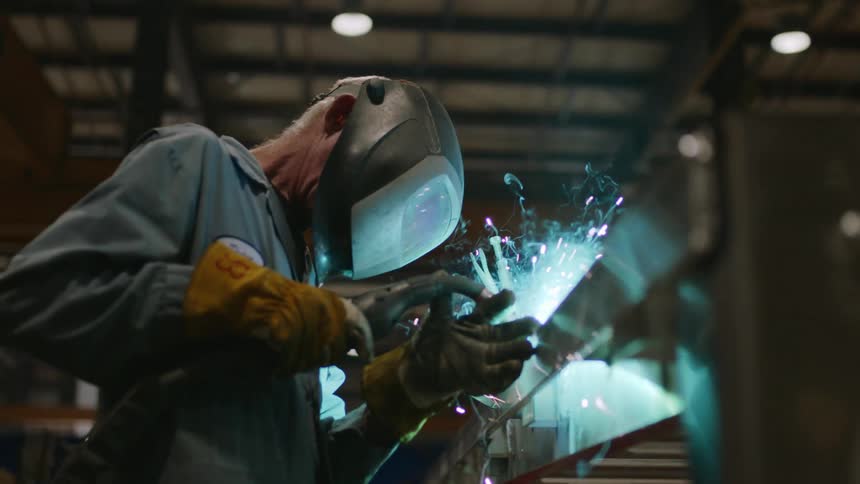 A welder is using a torch in the factory
