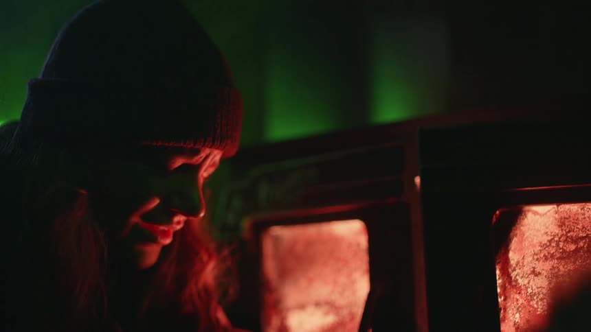 A fearful looking woman is scanned by a green laser in a building