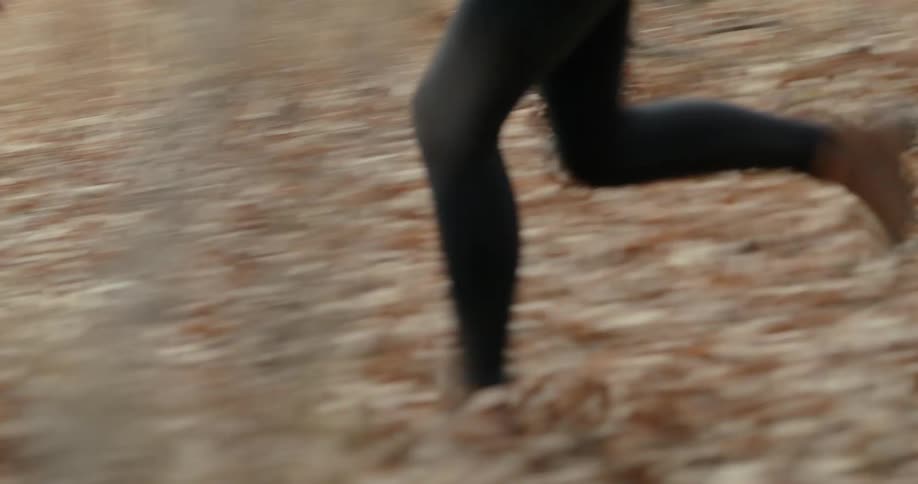 Legs of two people running through the forest