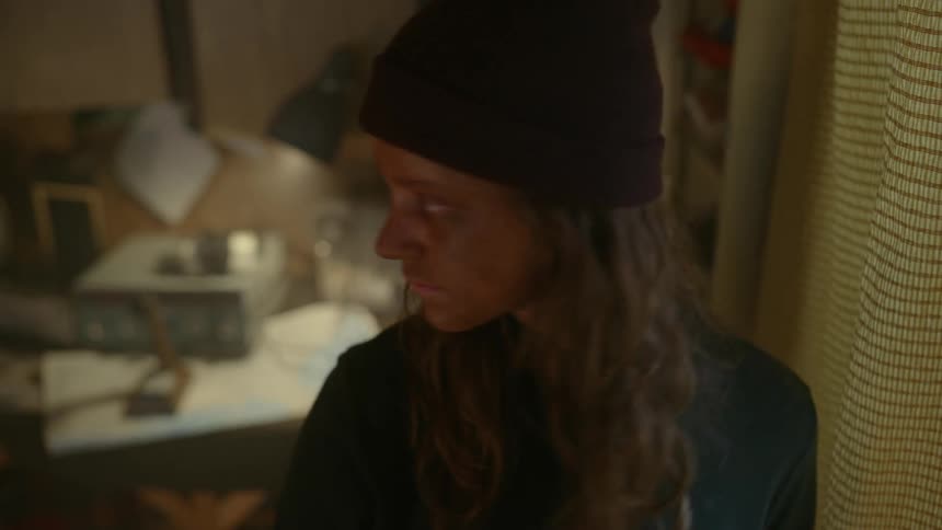 Young woman with a dirty face looking out the window and in the background a flashing light bulb