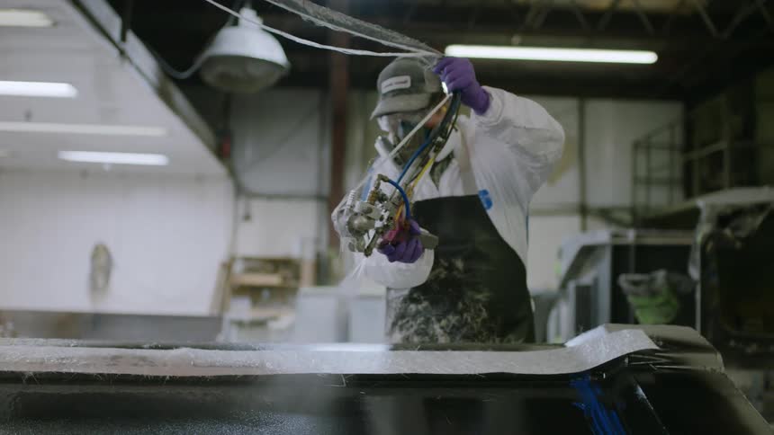 Person wearing a protective mask and specific clothing painting a metal sheet