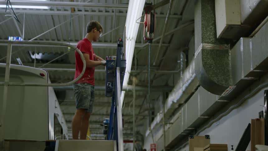Man in an industrial environment wearing a red tshirt and shorts operating
