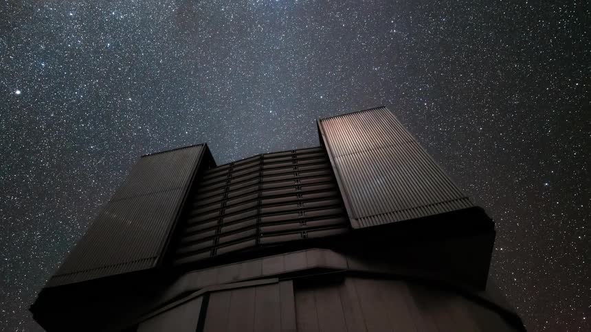 Large telescope in observatory pointed at a starry night sky