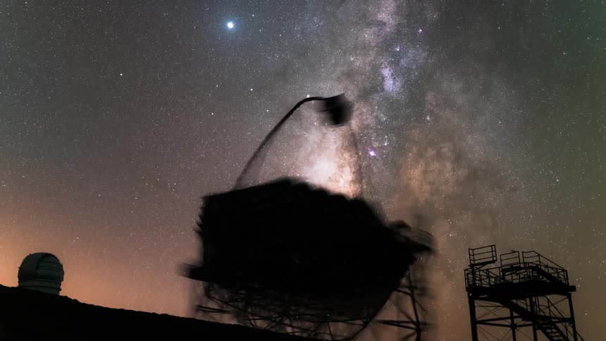 Silhouette of an antenna pointed at a starry sky at night
