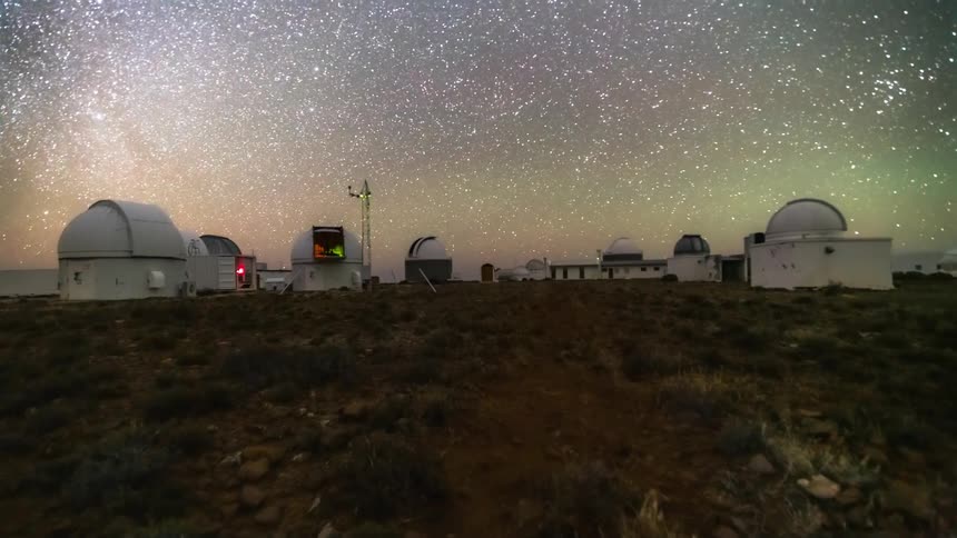 An observatory with multiple telescope domes under a star filled night sky
