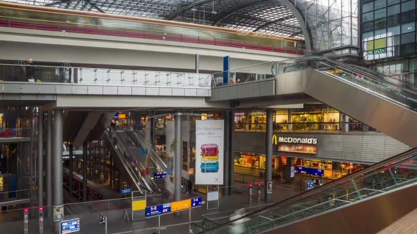 People move between shopping mall floors as public transit train makes a stop on top floor