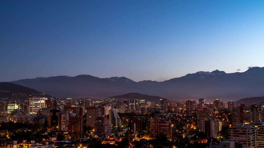 Panorama of a metropolis at night with a dawning day and silhouette of mountains on the horizon