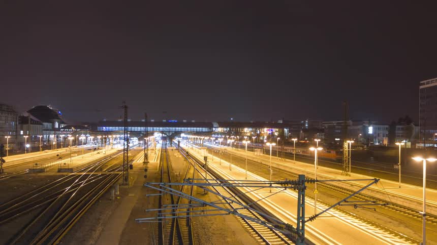 Trains move back and forth along the large set of tracks near a terminal at night