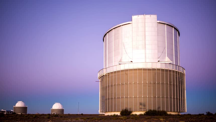 An observatory pointed at the white sky is in an environment with a dark sky and all stars