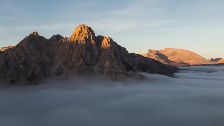 The peak of a mountain juts out from a sea of clouds at sunset