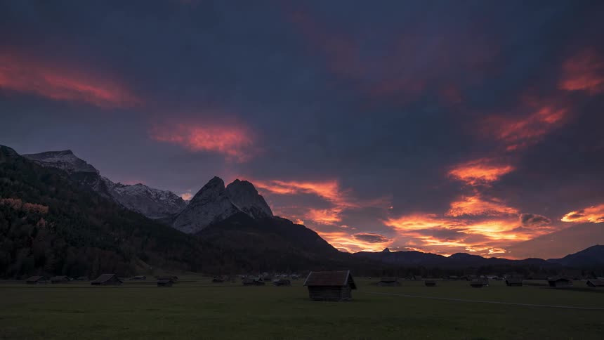Dark clouds float over mountains and a valley with a rural community