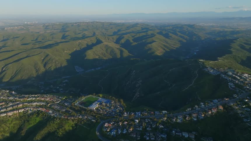Residential neighborhood tops ridge overlooking a shadowed valley on a hazy day
