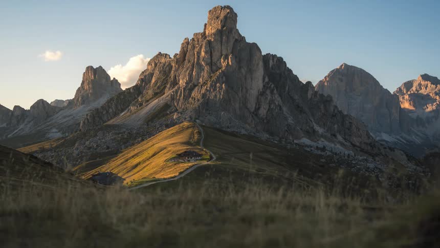Mountainous landscape at dusk with rocky peaks illuminated by golden light and undergrowth