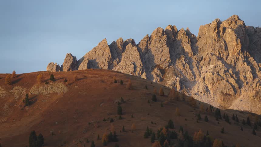 A hill with trees growing on it sits in front of a massive mountain