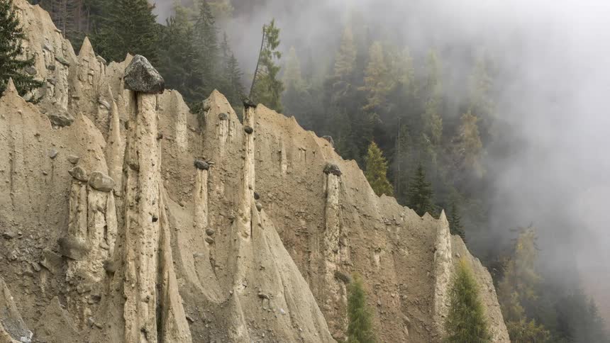Various rock formations like hoodoos with mist around them