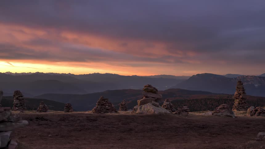 Stones stacked on top of each other above mountains against a stormy purple sky