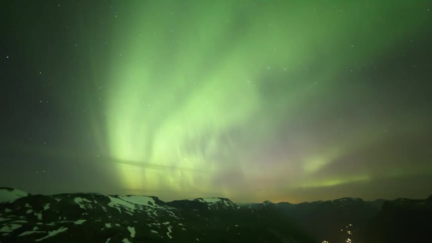 Green aurora over snowy mountains