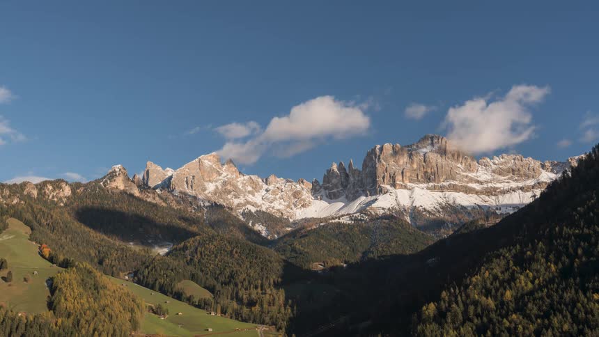 Greenish mountainous landscape with snowcapped peaks against a clear sky